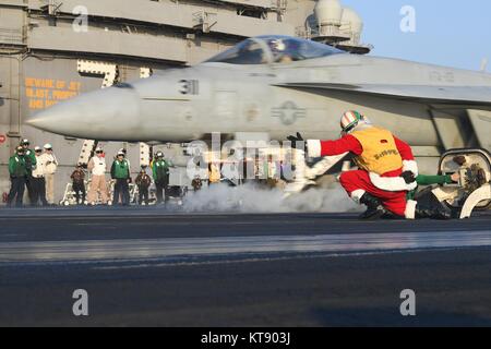 Ein U.S. Navy Matrose verkleidet als Weihnachtsmann, meldet eine F/A-18E Super Hornet Fighter auf dem Flugdeck der US Navy der Nimitz-Klasse Flugzeugträger USS Theodore Roosevelt Dezember 21, 2017 in den Arabischen Golf. Stockfoto