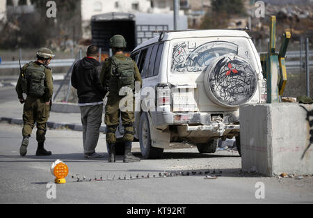 Hebron, West Bank, Palästina. 23 Dez, 2017. Israelische Soldaten überprüfen Sie die ID der Palästinensischen Treiber, wie Sie ein Fahrzeug an einem Checkpoint in der West Bank Stadt Hebron prüfen, am 23. Dezember 2017 Quelle: Wisam Hashlamoun/APA-Images/ZUMA Draht/Alamy leben Nachrichten Stockfoto