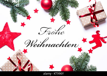 Der text Frohe Weihnachten in deutscher Sprache auf einem Weihnachten Hintergrund mit präsentiert rote Sterne Tannenzweigen und kopieren Raum in der Mitte auf weißem Hintergrund Stockfoto