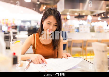 Frau Suchen im Menü für die Bestellung von Essen im Restaurant Stockfoto