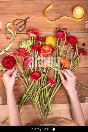 Ranunkulyus Bouquet von roten Blüten auf einem hölzernen Hintergrund Stockfoto