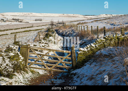 Alte hölzerne Tor auf einem Wanderweg in der Nähe von Rowarth, Derbyshire, England an einem verschneiten Wintermorgen. Stockfoto