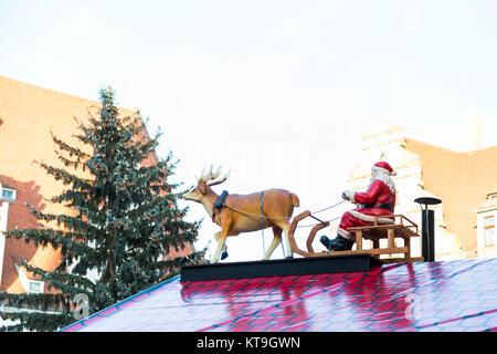 Weihnachten großen Kunststoff Holz- traditionelle dekorative Weihnachtsmann auf Schlitten mit Rotwild im Freien stehend auf dem roten Dach des Shop auf der Messe in der Stadt Mich Stockfoto