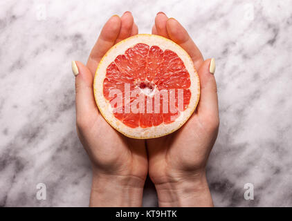 Weibliche Hände halten Schnitt Grapefruit Stockfoto