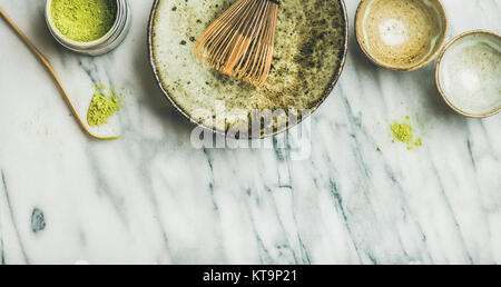 Flachbild-lay von japanischen Werkzeugen und Schalen für die Zubereitung von Matcha Tee. Matcha Pulver in Blechdose, Chashaku Löffel, Chasen Bambusbesen, Chawan Schüssel, Tassen für Cere Stockfoto