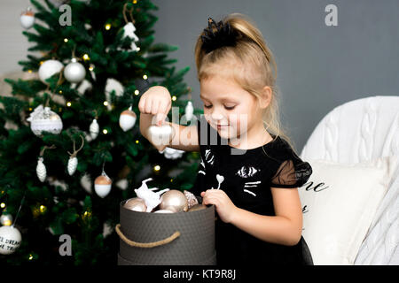 Kleines Mädchen schmücken einen Weihnachtsbaum. Frohe Weihnachten und schöne Feiertage. Stockfoto