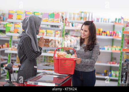 Glückliche junge asiatische Frau Krämer oder Kassierer Begrüßung des Kunden im Supermarkt Stockfoto