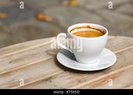 Eine Nahaufnahme eines weißen Tasse griechischen heißen Kaffee mit einer Platte auf einem hölzernen Tisch im Freien, Sonne Licht. Stockfoto