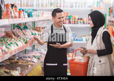 Portrait der männlichen Ladenbesitzer hilft muslimischen Frauen Kunde im Supermarkt Stockfoto