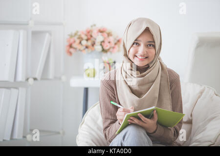 Portrait von schöne asiatische Frau mit Kopftuch schriftlich etwas Stockfoto