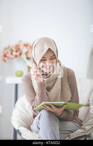 Portrait von Angeregten asiatische Frau mit Hijab genießen Sie etwas schreiben Stockfoto