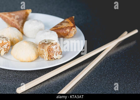 Leckeres Sortiment an hausgemachten Asiatische Gebäck. Samosas mit einer Blume und Banane Kugeln Stockfoto