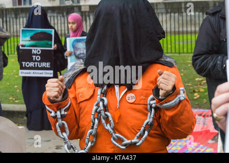 Eine Demonstrantin trägt manacles und Shaker Aamer ist Gefängnis Nummer 239 auf der 5000 Tag der seine illegale Inhaftierung in Guantanamo. Hinter ihr sind die Ehefrau und die Tochter des Shawki Ahmed Omar, im Gefängnis im Irak seit 2004. Stockfoto