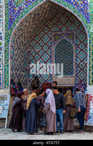 Eine Gruppe von Frauen, die Einkaufsmöglichkeiten für Souvenirs in der Sher Dor Madrassa, der Registan, Samarkand, Usbekistan Stockfoto