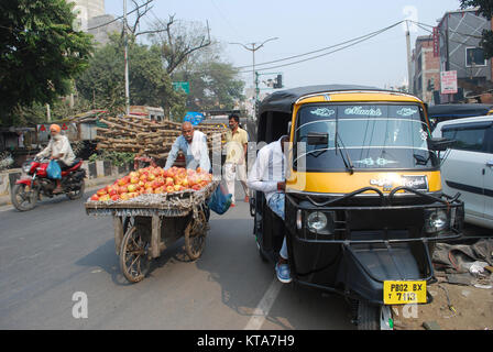 Ein Tuk Tuk und eine Frucht Verkäufer auf einer belebten Straße in einer Straßenszene in Amritsar, Punjab, Indien Stockfoto