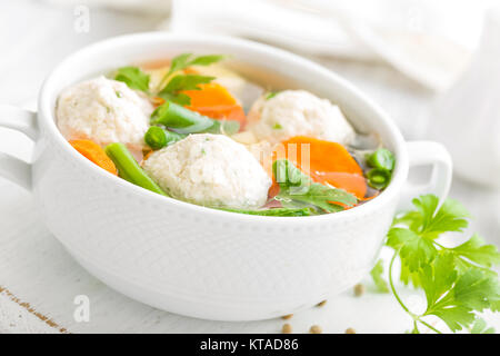 Frische Hühnersuppe mit Gemüse und Fleischbällchen in einer Schüssel auf weißem Hintergrund. Ansicht von oben Stockfoto