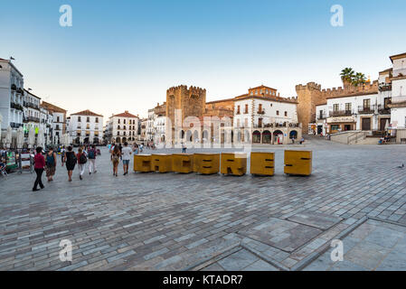 Morgen Blick von Menschen zu Fuß auf dem Hauptplatz, der Plaza Mayor, in Caceres, Spanien mit Ciudad Monumental im Hintergrund Stockfoto