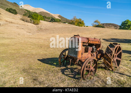 Alten verrosteten Traktor in einem offenen Feld in San Luis Obispo County, Kalifornien sitzen. Stockfoto