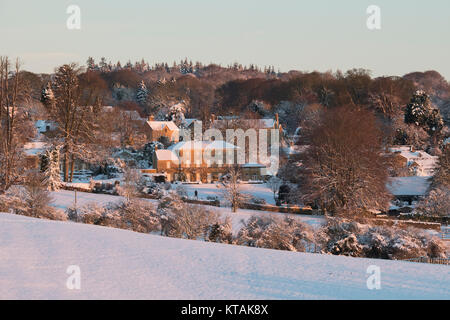 Bourton auf der Hill Manor Haus im Schnee bei Sonnenaufgang im Dezember. Bourton auf dem Hügel, Cotswolds, Gloucestershire, England. Stockfoto