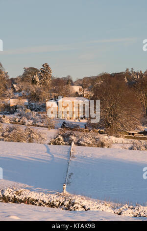 Bourton auf der Hill Manor Haus im Schnee bei Sonnenaufgang im Dezember. Bourton auf dem Hügel, Cotswolds, Gloucestershire, England. Stockfoto