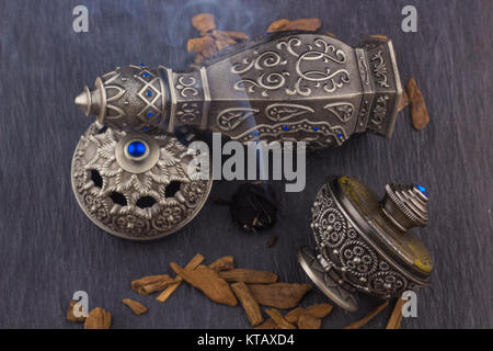 Silber-Oriental künstlerische arabischen Oud Parfüm / arabischen Oud-Duft mit Oud duftende Holz verbrannt im Hintergrund mit duftenden Rauch in der Luft Stockfoto