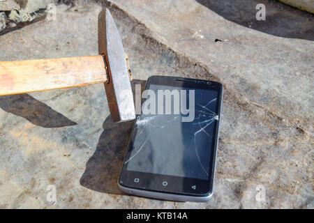 Hammer und Smartphone. Der Bildschirm des Smartphones, eine defekte ha Stockfoto