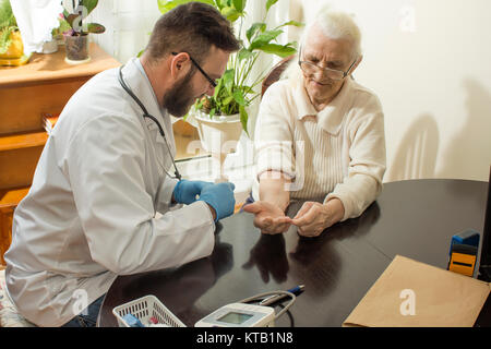 Eine private Arztpraxis. Arzt untersucht die Hand einer alten Frau. Stockfoto
