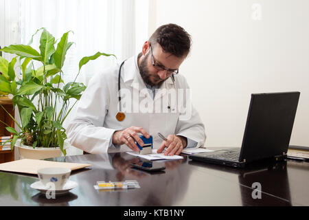 Die Hand des Arztes ist auf das Rezept gestempelt, der Arzt schreibt ein Rezept an seinem Schreibtisch. Stockfoto