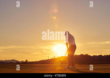 Mann spielt Golf ion am Abend Stockfoto