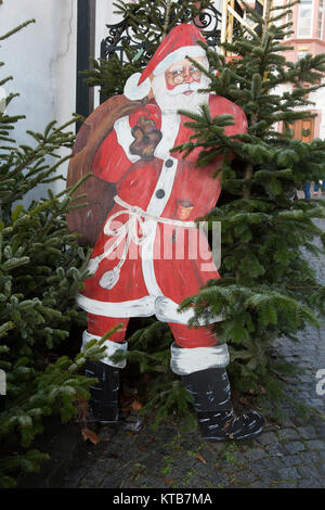 Eine hölzerne Weihnachtsmann steht lehnte sich an einen Baum. Die 24 RŸdesheim Weihnachtsmarkt der Nationen in RŸdesheim, Deutschland befindet sich in der Altstadt von gehalten Stockfoto