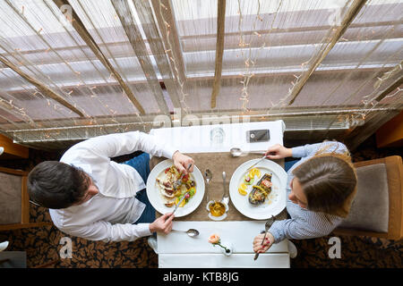 Essen, Weihnachten, Feiertage und Personen Konzept - lächelndes Paar essen Hauptgang im Restaurant Stockfoto