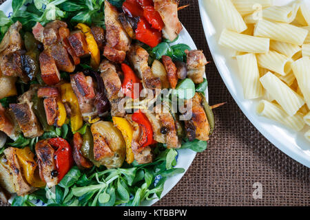 Gegrillte Fleischspieße - gegrilltes Schweinefleisch Kebab mit roten und gelben Paprika auf einem Teller mit Gemüse Stockfoto