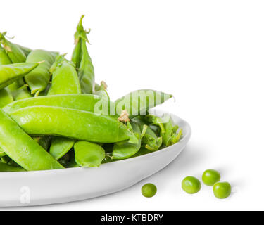 Closeup Haufen grüne Erbsen in Hülsen in weiße Platte Stockfoto