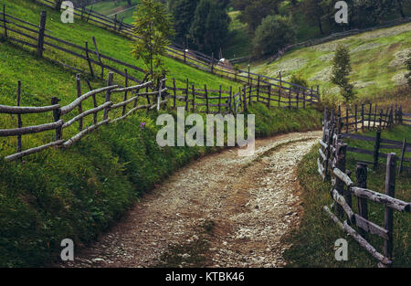 Land straße und rustikalen Holzmöbeln Zäune in einem traditionellen siebenbürgischen Dorf, Brasov, Rumänien. Stockfoto