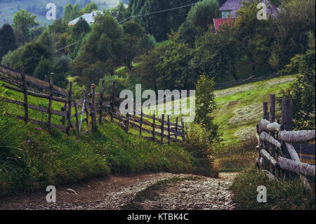 Land straße und rustikalen Holzmöbeln Zäune in einem traditionellen siebenbürgischen Dorf, Brasov, Rumänien. Stockfoto