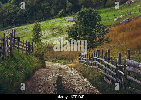 Land straße und rustikalen Holzmöbeln Zäune in einem traditionellen siebenbürgischen Dorf, Brasov, Rumänien. Stockfoto