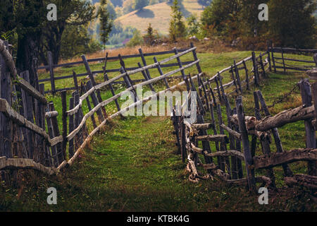 Ländliche Szene mit Fußweg und rustikalen hölzernen Zaun in einem traditionellen siebenbürgischen Dorf, Brasov, Rumänien. Stockfoto