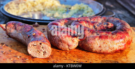 Leckere Würstchen auf Holzplatte auf Barbecue Grill zubereitet Stockfoto