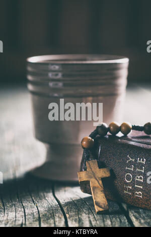 Rosenkranz, Bibel und Kelch mit Wein. Stockfoto