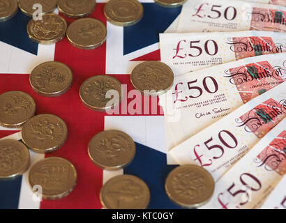 Pound Münzen und Banknoten, Großbritannien über Flagge Stockfoto