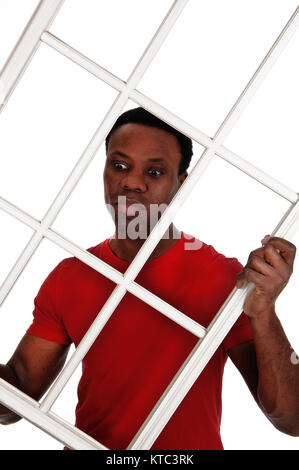 Angst suchen African American man einen weißen Fensterrahmen in einem roten T-Shirt, auf weißem Hintergrund Stockfoto