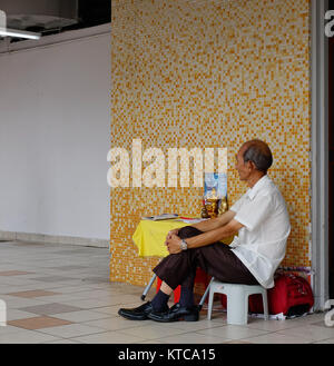 Singapur - Dec 14, 2015. Ein Mann auf dem Markt in Chinatown, Singapur sitzen. Singapur ist ein souveräner Stadtstaat in Südostasien, und die Welt auf Stockfoto