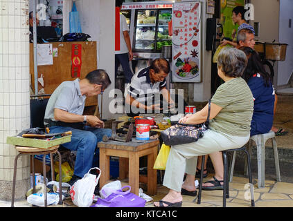 Singapur - Dec 14, 2015. Menschen Reparatur Schuhe auf dem Markt in Chinatown, Singapur. Singapur ist ein souveräner Stadtstaat in Südostasien, und die wo Stockfoto