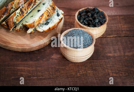 Mohn und Rosinen in Holz- Schalen auf einem braunen Oberfläche Stockfoto