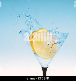 Frische Zitrone im Glas mit Wasser spritzen Stockfoto