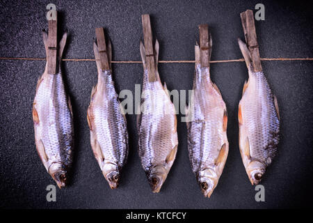 Getrockneter Fisch Eintopf hängen an Wäscheklammern auf einem Seil Stockfoto