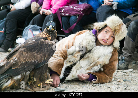 Junge Adler Jägerin frisst einen Lutscher, während Sie Ihre biegen Sie an der Golden Eagle Festival in der Mongolei wartet Stockfoto