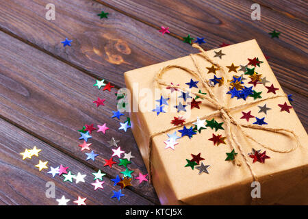 Geschenkbox mit Stern. Kreatives Konzept mit festlichen Dekor auf schwarzen Hintergrund. Konfetti Sterne, rot, gelb, mit Geschenkverpackung. Explosion von Konfetti. Stockfoto