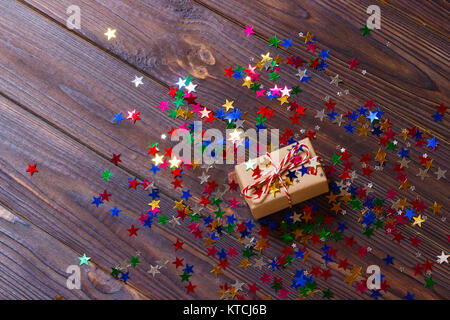 Geschenkbox mit Stern. Kreatives Konzept mit festlichen Dekor auf schwarzen Hintergrund. Konfetti Sterne, rot, gelb, mit Geschenkverpackung. Explosion von Konfetti. Stockfoto