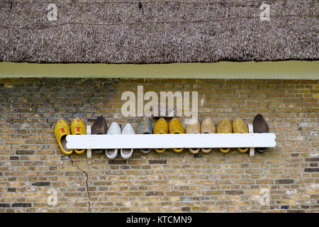 Reihe der Holzschuhe hängen unter dem Dach an der Wand Stockfoto